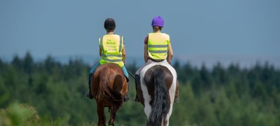two riders on horses wearing BHS hi vis